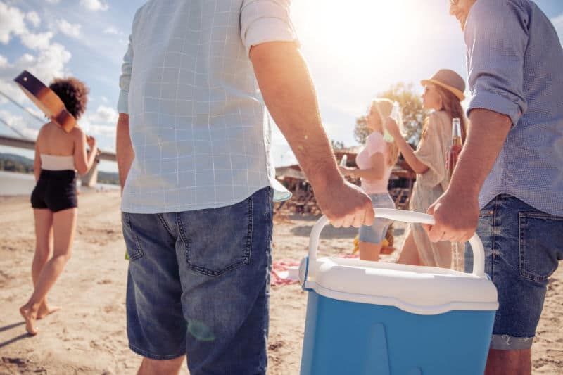 Friends carrying the best esky Australia at the beach.