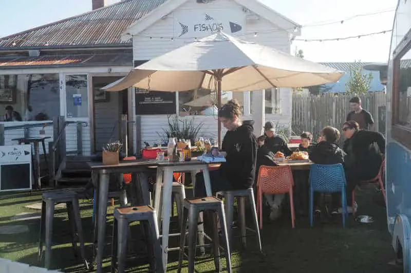People eating outdoors under umbrellas at Fisho's one of the most popular restaurants in Torquay.