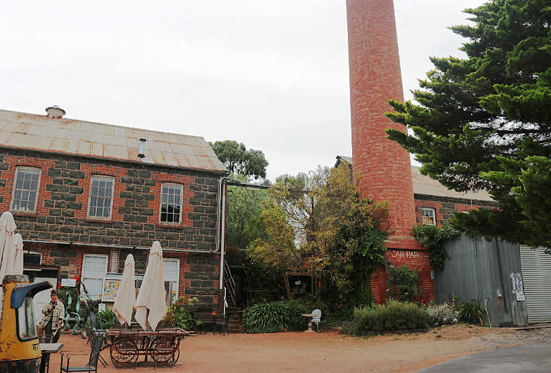 View of the old papermills in Fyansford with chimney stack, cafe, umbrellas, and the papermill gallery.