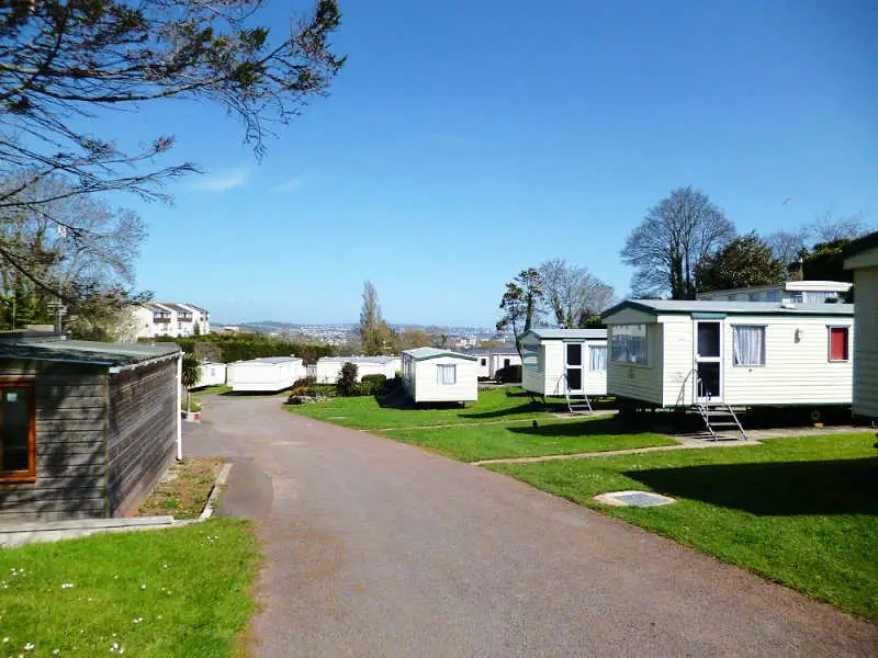 Image of holiday cabins, lush green grass, and a road at Geelong caravan parks