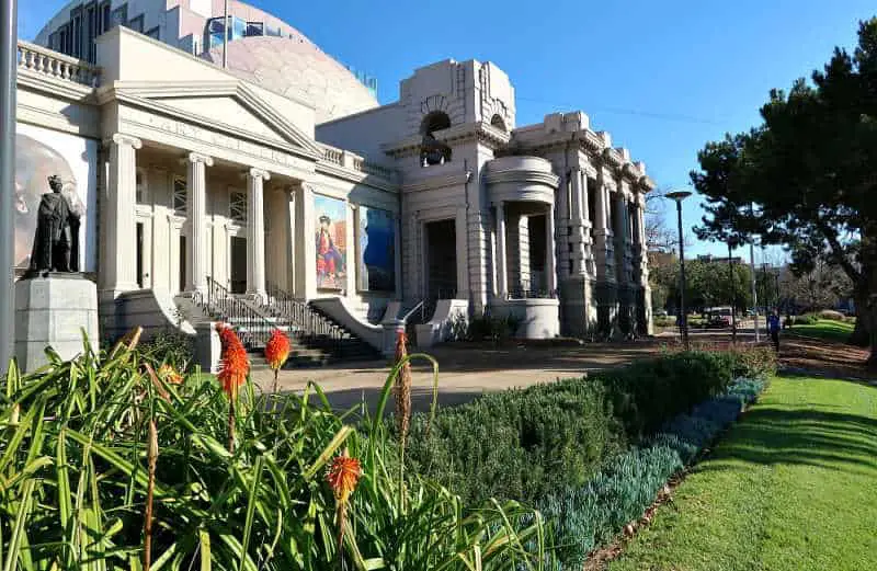 Rear view of Geelong Gallery in Johnstone Park with flowers, a statue and art work.