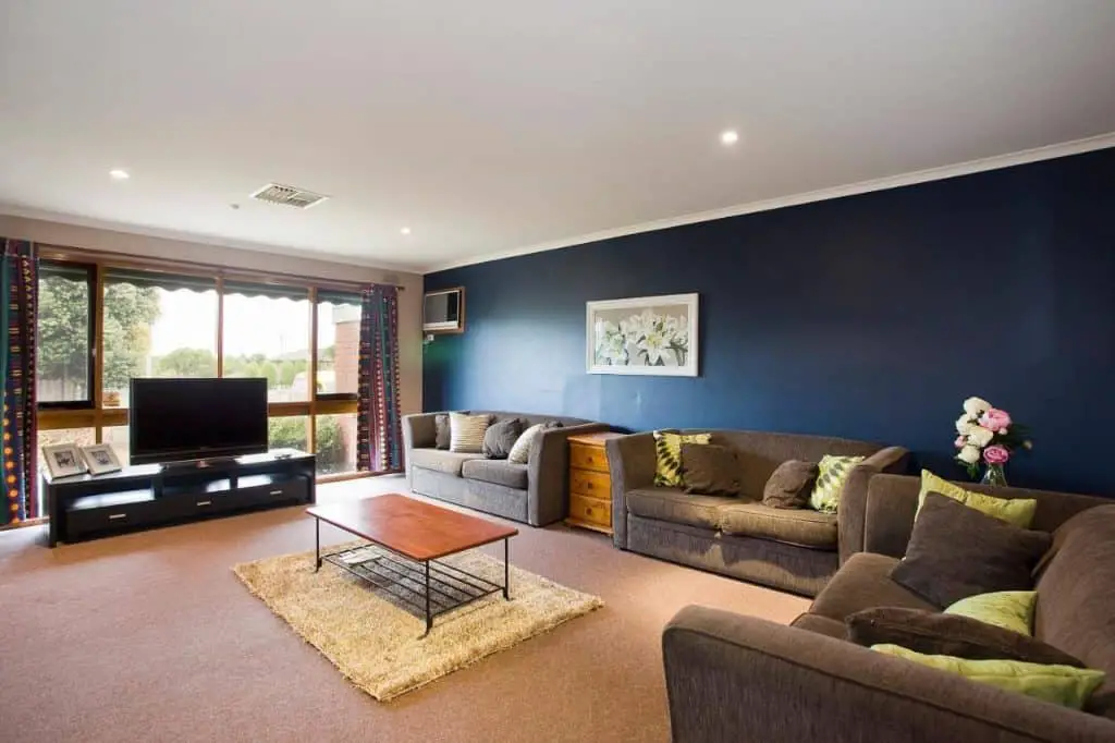 Feature wall and lounge in the living room of Geelong Holiday Home.