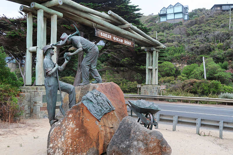 View of the Great Ocean Road Memorial Arch also known as the Great Ocean Road sign with the returned soldiers sculpture in the foreground.