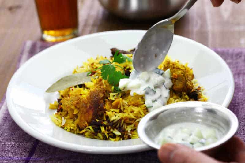 Biryani with yogurt being added at the best Indian restaurant Geelong.