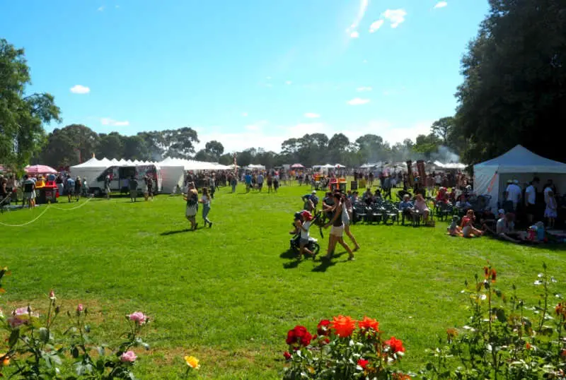 People strolling the lush lawns at the Lara Food and Wine Festival with roses in the foreground.