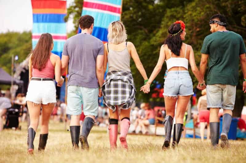 Group of friends walking and holding hands at Meredith Music Festival.