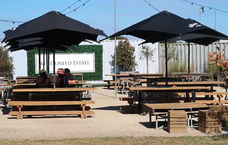 People sitting at tables and chairs under umbrellas at Mount Duneed Estate. One of the best wineries in Geelong.