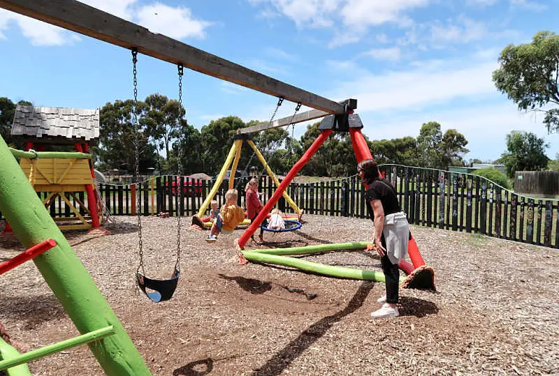 Small boy being pushed on the swings at the Narana Geelong playground.