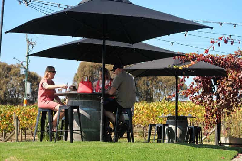People drinking wine under black umbrellas at Nicol's Winery in Geelong.