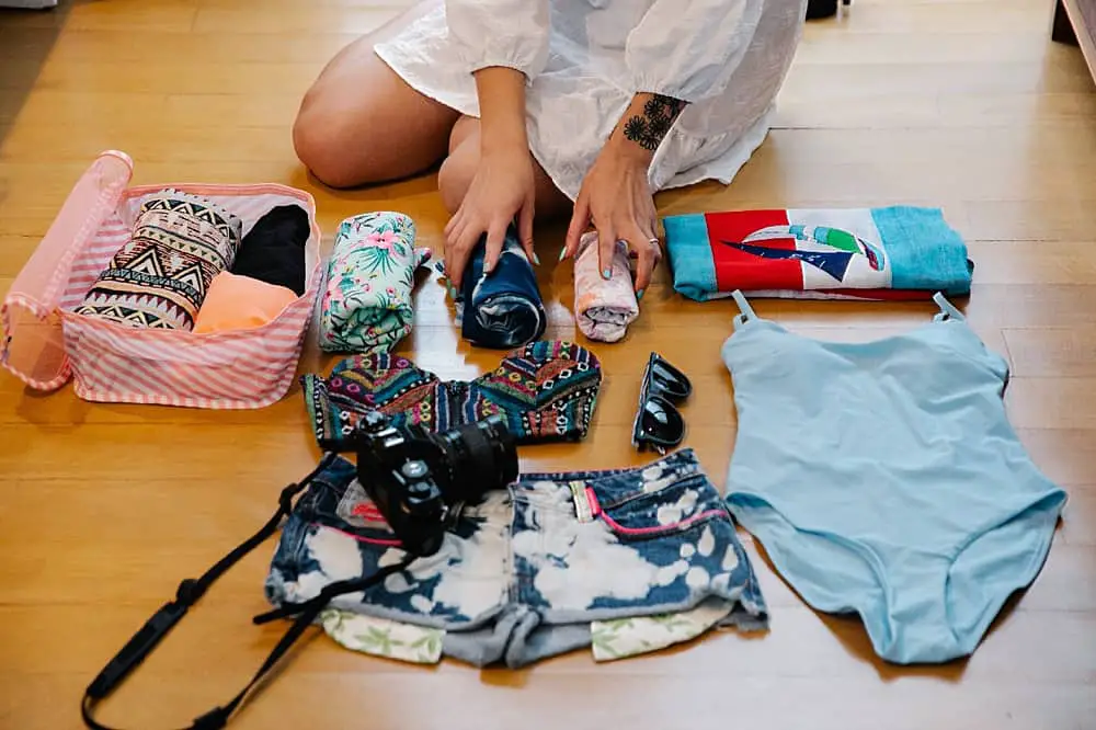 Partial view of a woman sitting on the floor sorting through beach gear. 