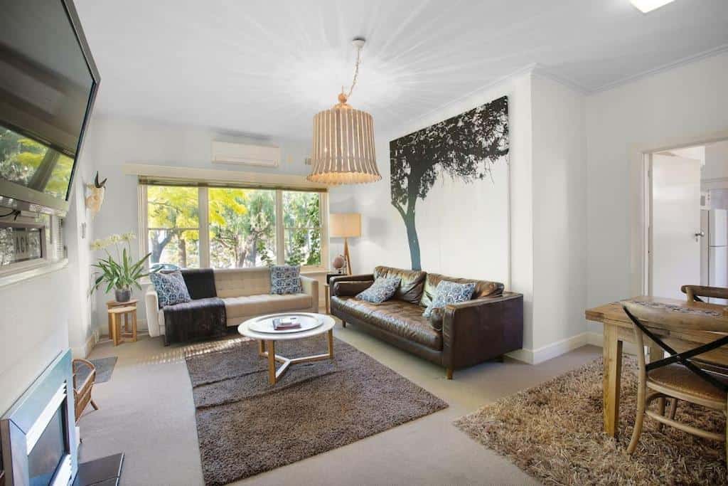 Living area with lounge and large windows at The Beach House self-contained accommodation in Geelong.