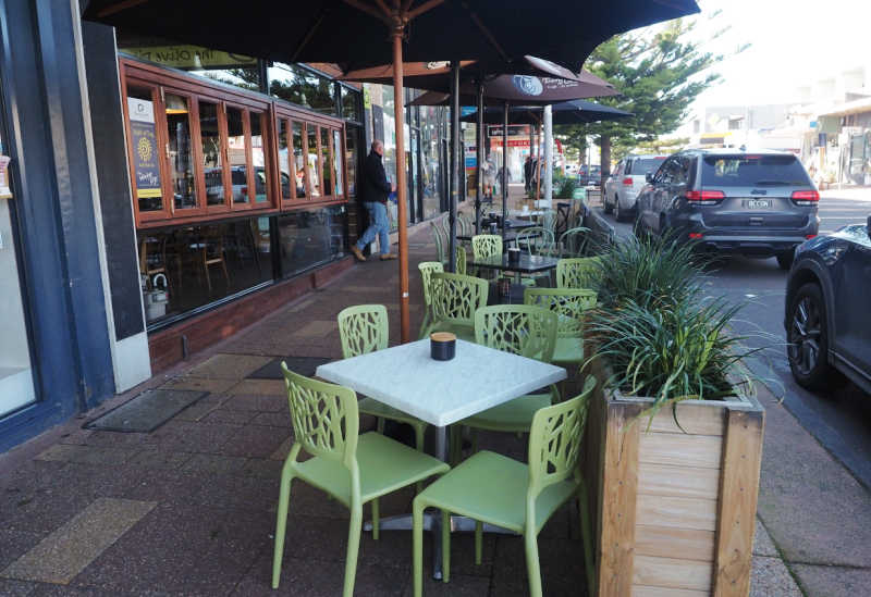 Green tables and umbrellas outside the Olive Pitt Delicatessen in Ocean Grove. 