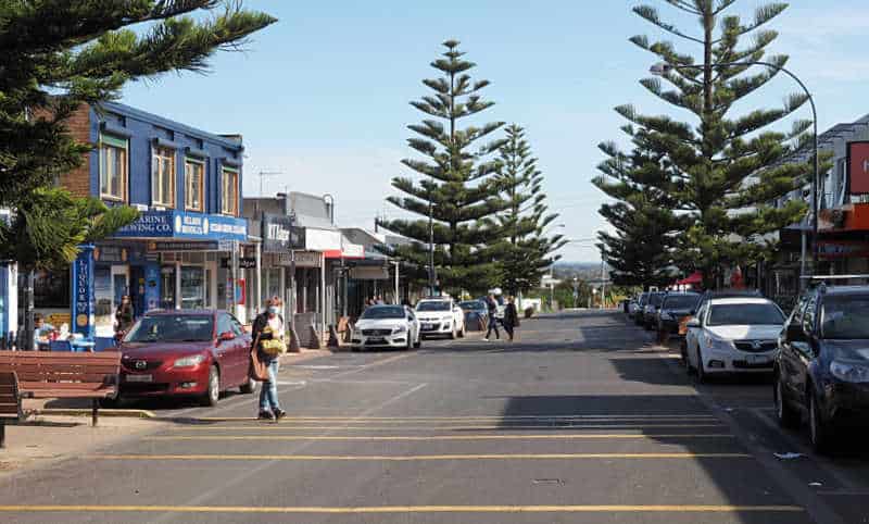 The Terrace at Ocean Grove with pine trees and shoppers crossing the street.